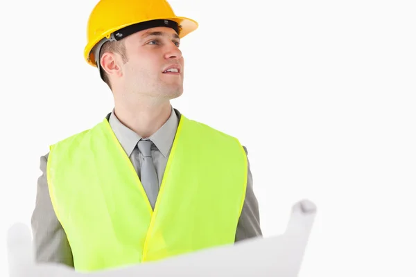 Builder holding a plan while looking around — Stock Photo, Image
