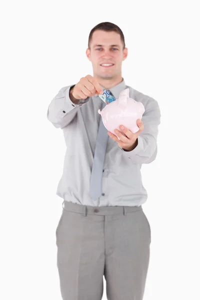 Porträtt av en affärsman som att sätta en anteckning i en spargris — Stockfoto