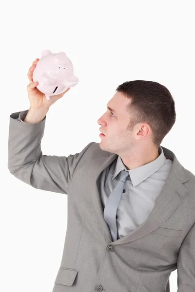 Porträt eines Geschäftsmannes, der in ein Sparschwein blickt — Stockfoto