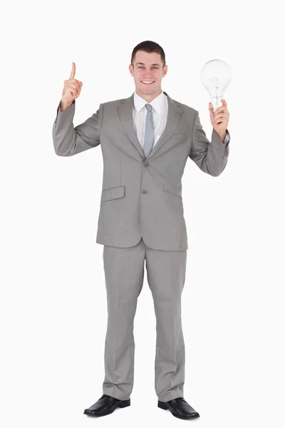 Porträt eines Geschäftsmannes, der eine Glühbirne hält und auf jemanden zeigt — Stockfoto