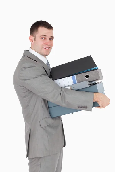 Portrait of a young businessman holding a stack of binders — Stockfoto