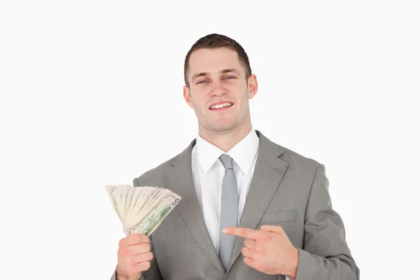Empresário apontando para um maço de dinheiro — Fotografia de Stock