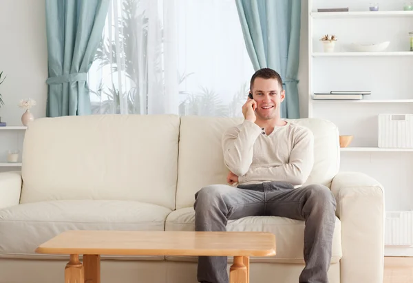 Homem ao telefone enquanto sentado em seu sofá — Fotografia de Stock
