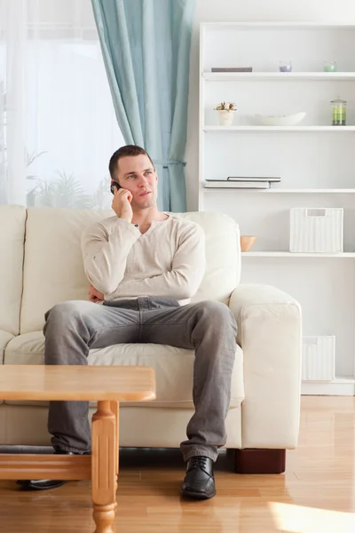 Portrait of a man on the phone while sitting on his sofa — Stock Photo, Image