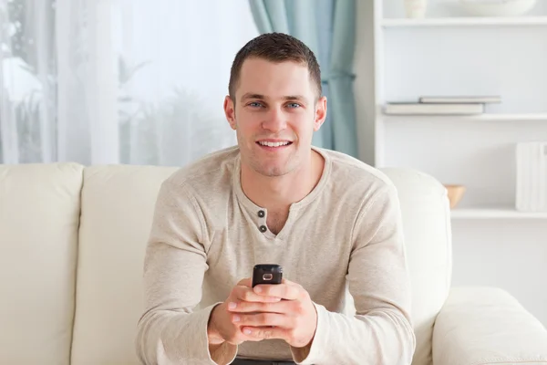 Mann verschickt SMS, während er auf einem Sofa sitzt — Stockfoto