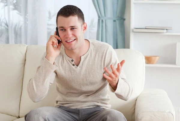 남자는 전화를 통해 얘기 하는 동안 소파에 앉아 — 스톡 사진