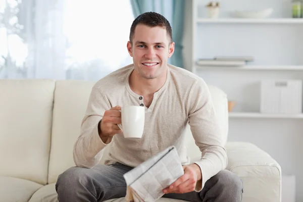 Человек, держащий газету за чашкой чая — стоковое фото