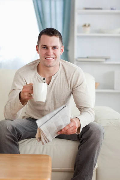 Портрет человека, держащего газету за чашкой чая — стоковое фото
