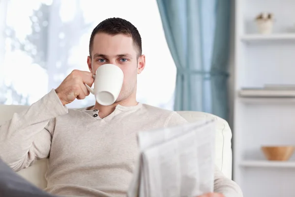 Hombre guapo tomando un té mientras lee las noticias — Foto de Stock