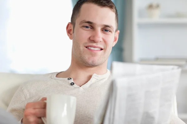 微笑阅读新闻时喝茶的男人 — 图库照片
