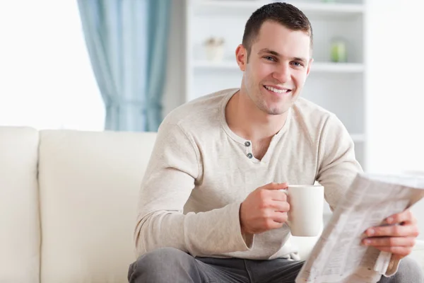 Hombre feliz tomando un té mientras lee las noticias — Foto de Stock