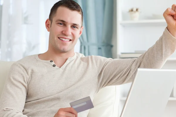 Smiling man shopping online with the fist up — Stock Photo, Image