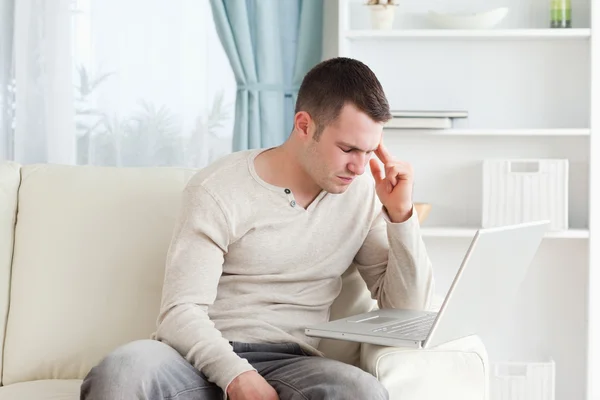 Hombre que tiene dolor de cabeza mientras usa una computadora portátil —  Fotos de Stock