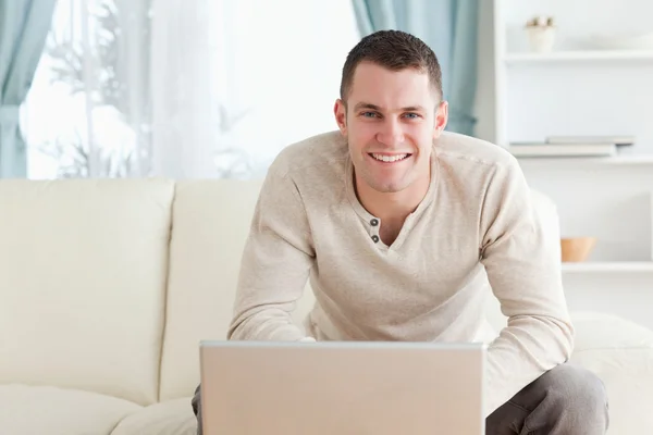 Leende ung man använder en bärbar dator — Stockfoto