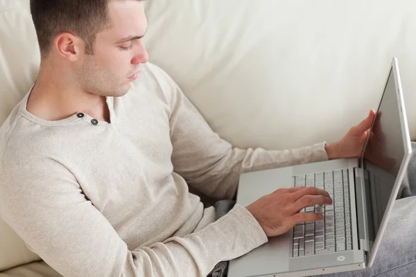 Iyi görünümlü bir adam ile bir dizüstü bilgisayar rahatlatıcı — Stok fotoğraf