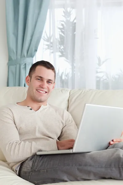 Портрет улыбающегося человека, расслабляющегося с ноутбуком — стоковое фото