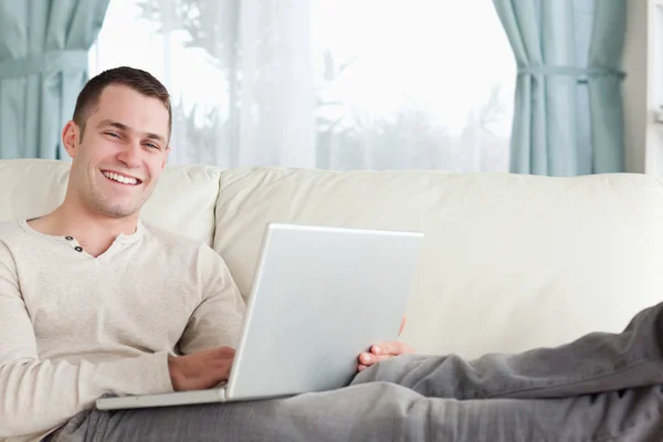 Glimlachende man ontspannen met een laptop — Stockfoto