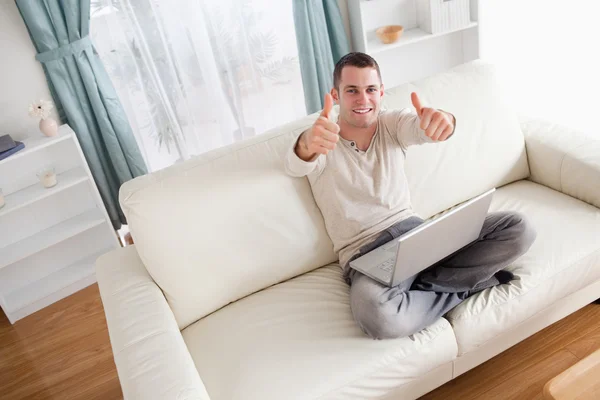 Man ontspannen met een laptop met de duimen omhoog — Stockfoto