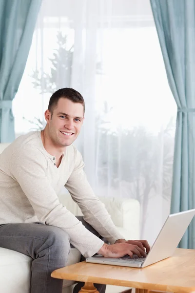 Retrato de um homem sorridente digitando em seu laptop — Fotografia de Stock