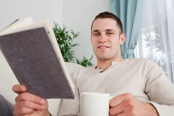 Чоловік тримає чашку кави і книгу — стокове фото