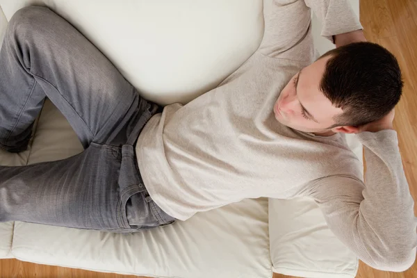 Молодой человек лежит на диване — стоковое фото