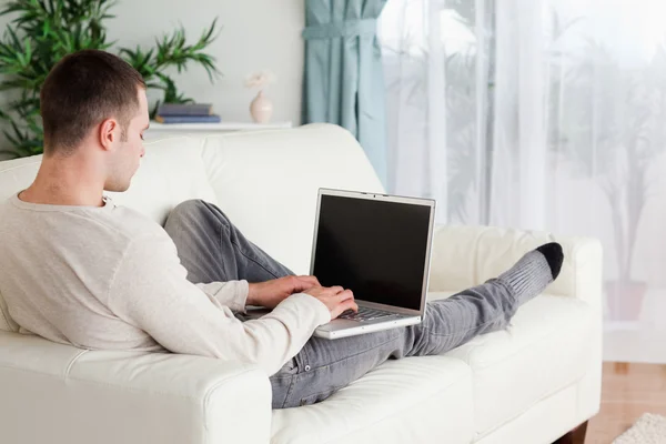 Man liggande på sin soffa som använder en bärbar dator — Stockfoto