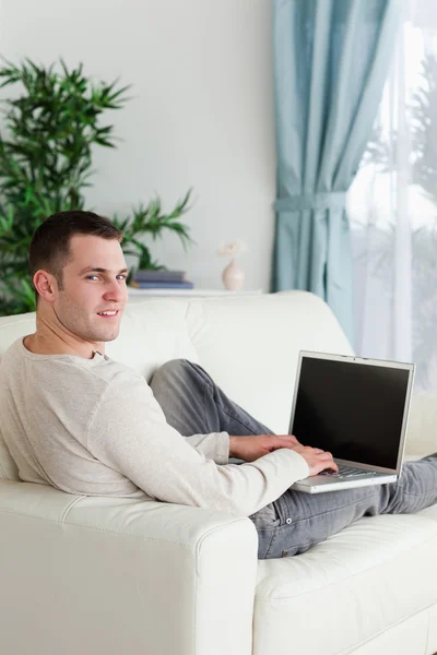 Porträtt av en man liggande på sin soffa med en bärbar dator — Stockfoto