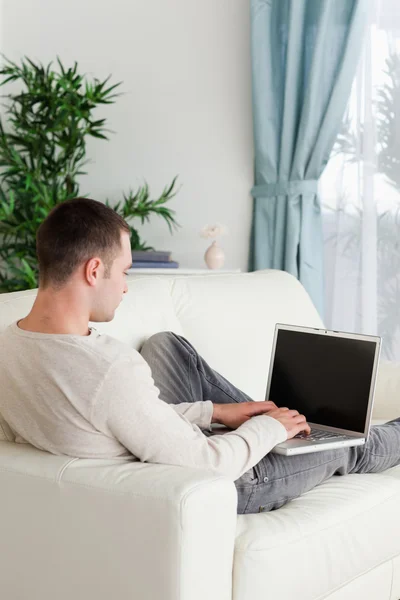Porträtt av en man liggande på sin soffa som använder bärbar dator — Stockfoto