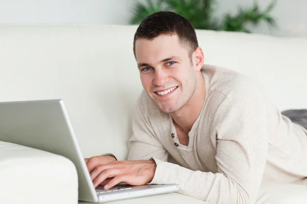Man lying on a sofa with a laptop — Stock Photo, Image