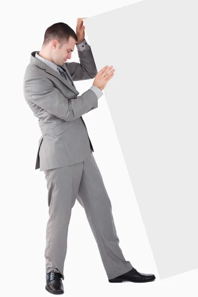 Retrato de empresário empurrando um painel em branco — Fotografia de Stock
