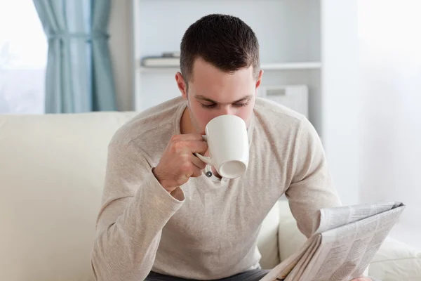 Mladý muž čtení zprávy zároveň s kávou — Stock fotografie