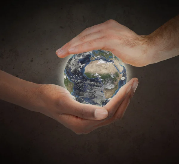 Due mani che proteggono un globo luminoso del pianeta — Foto Stock