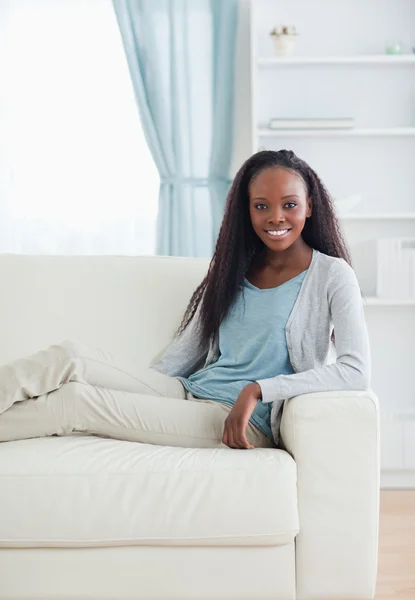 Mujer sonriente sentada con las piernas en el sofá —  Fotos de Stock