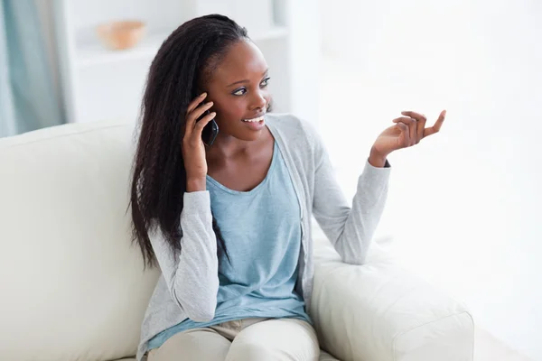 Woman talking on the phone while sitting in the living room — Stock Photo, Image
