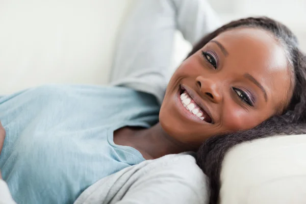 Close up de mulher sorridente tendo um descanso no sofá — Fotografia de Stock