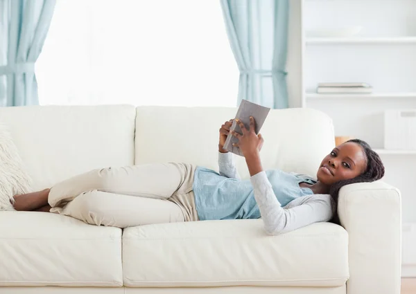 女人躺在沙发上读一本书 — 图库照片