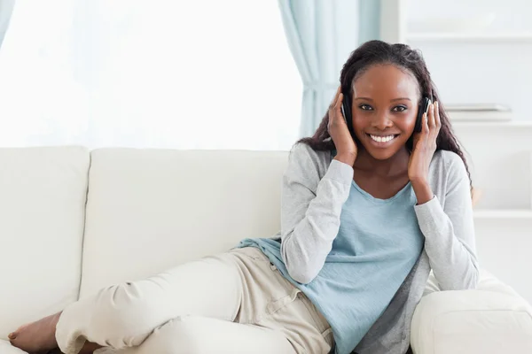 Vrouw ontspannen op de sofa met koptelefoon op — Stockfoto