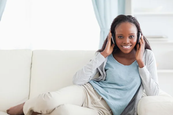 女人戴着耳机在沙发上放松 — 图库照片
