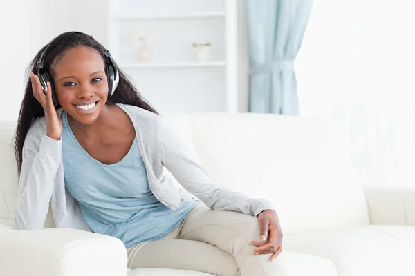 Woman sitting on couch with headphones on — Stock Photo, Image
