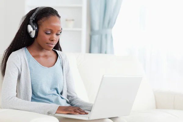 Kobieta z słuchawkami na pracy na laptopie — Zdjęcie stockowe