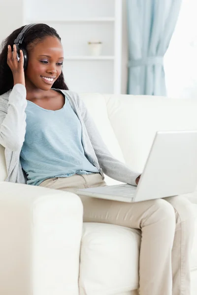 Frau hört Musik während sie ihren Laptop benutzt — Stockfoto