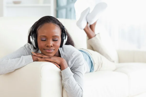 Mulher com os olhos fechados curtindo música em seu sofá — Fotografia de Stock