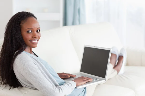 Lachende vrouw met laptop op sofa — Stockfoto