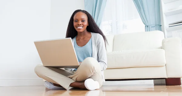 Kobieta siedzi na podłodze przy użyciu swojego laptopa — Zdjęcie stockowe