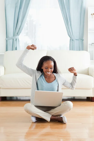 Woman stretching while sitting on the floor with notebook — Stock Photo, Image