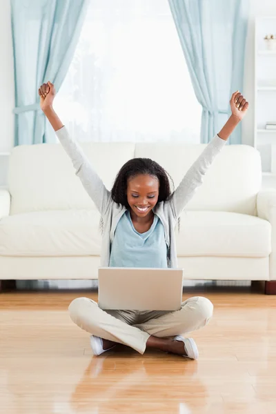 Woman stretching while sitting on the floor with her laptop — Stock Photo, Image