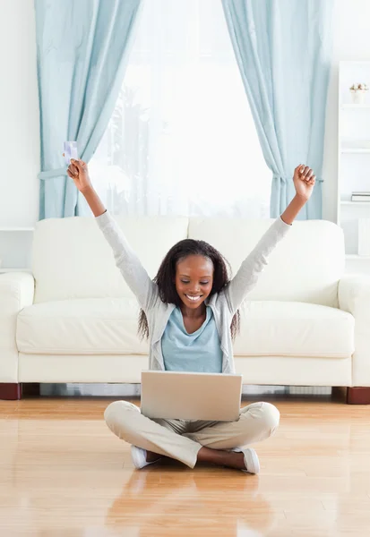Young woman stretching while sitting on the floor with laptop — Stock Photo, Image