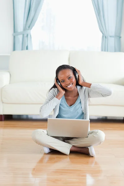 Kvinna sitter på golvet och lyssnar på musik — Stockfoto