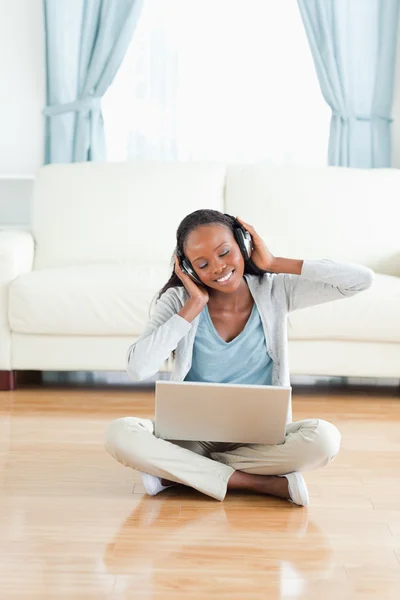 Woman sitting on floor listening to music — Stock Photo, Image