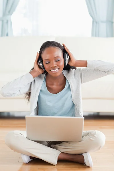 Close up of woman sitting on the floor listening to music — Stock Photo, Image